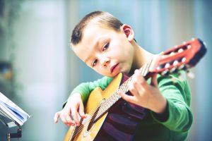 Little boy is playing the guitar at home